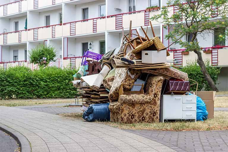Curbside furniture pickup featuring a pile of discarded couches, chairs, and boxes, highlighting the need for responsible furniture recycling and disposal options.