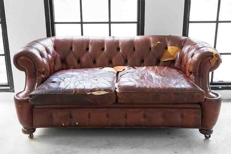 worn out leather soda ready for couch removal service from Garbage Gurus