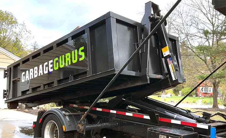 Garbage Gurus roll-off dumpster in Fitchburg, MA, showcasing efficient waste disposal service for cleanouts and renovations.