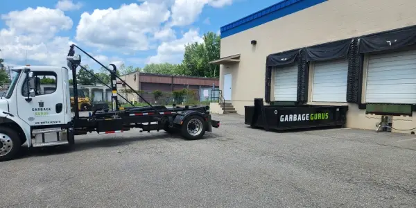 Garbage Gurus truck dropping off a dumpster at a warehouse for a commercial cleanout