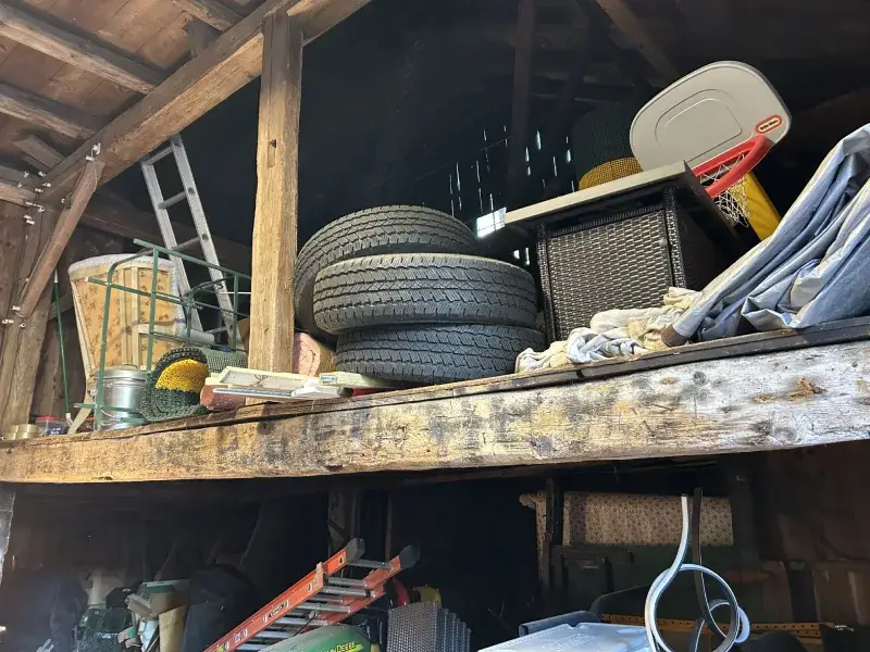 barn space filled with older tires, kids toys, and other household junk representing Barn Cleanout Service in the North Central MA region