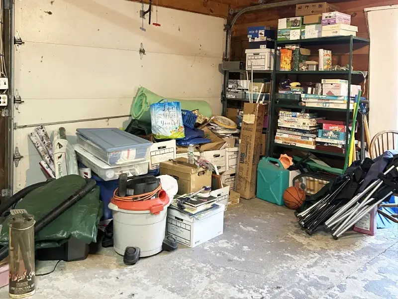 Inside of garage stall showing stacked boxes, plastic totes, tools, and other equipment