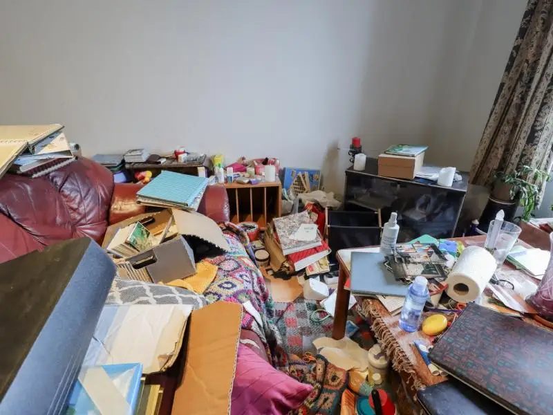 Small bedroom with clutter all over the floor and bed representing hoarder cleanout service for homes and rental properties in North Central MA