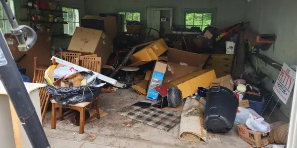 garage space filled with cardboard boxes, old carpeting, trash bags, broken furniture and other household items and recyclables representing residential property cleanout service for homes in North Central MA